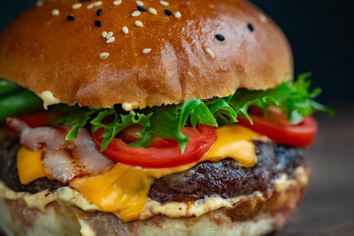 Cheeseburger with melted cheese, lettuce, tomato, and bacon on a toasted bun.