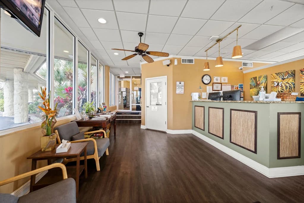 Cozy living room with sofa, armchair, coffee table, and bar seating next to a kitchenette.