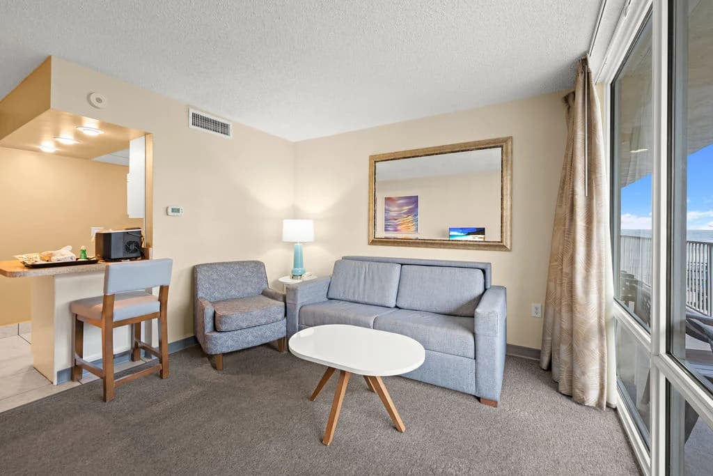 Modern living room with a gray sofa, armchair, and large window view.
