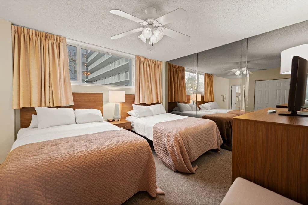 Cozy bedroom with twin beds, mirrored wall, and ceiling fan, featuring warm decor.